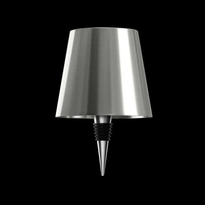 AMBIENTIFY Bottle wireless LED lamp fitted onto a wine bottle, placed on an outdoor garden table surrounded by natural greenery. Soft warm ambient glow, touch-dimmable in 3 levels, USB-C rechargeable table lamp for home décor.