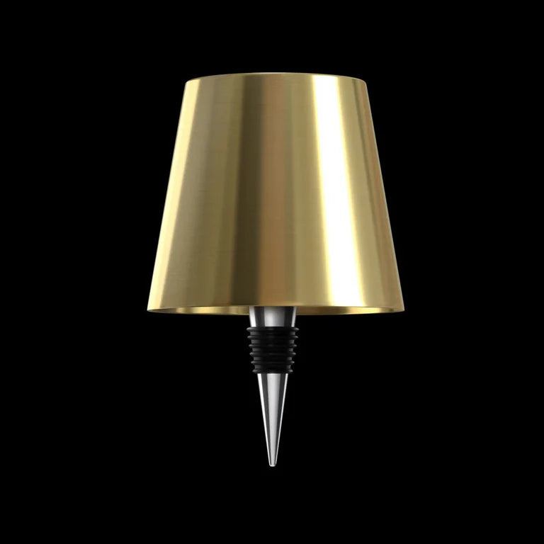 AMBIENTIFY Bottle wireless LED lamp fitted onto a wine bottle, placed on an outdoor garden table surrounded by natural greenery. Soft warm ambient glow, touch-dimmable in 3 levels, USB-C rechargeable table lamp for home décor.