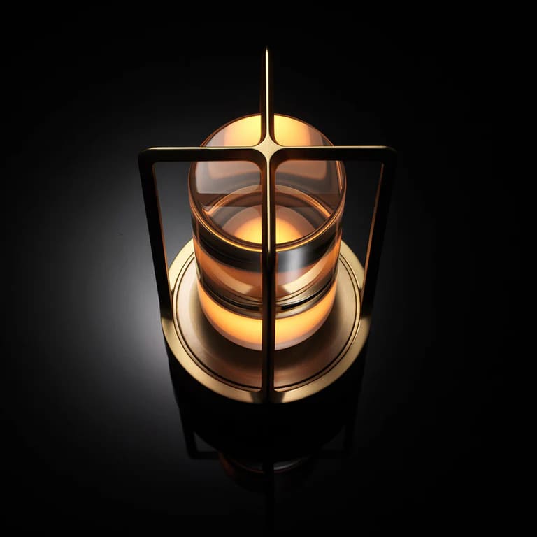 AMBIENTIFY Retro cordless retro table lantern lamp casting a warm amber glow, placed on a wooden tray. Slender aluminium frame with cylindrical acrylic glass shade. Atmospheric home décor lighting for bedroom, living room or outdoor use.