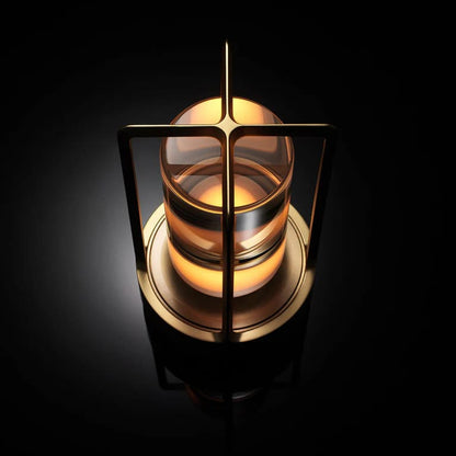 AMBIENTIFY Retro cordless retro table lantern lamp casting a warm amber glow, placed on a wooden tray. Slender aluminium frame with cylindrical acrylic glass shade. Atmospheric home décor lighting for bedroom, living room or outdoor use.