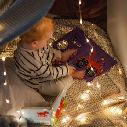 Campify String fairy light reel held in hand at night, showing warm amber LED string lights extended across dark outdoor ground, compact hub glowing with blue charge indicator, IP67 waterproof camping and home fairy lights.