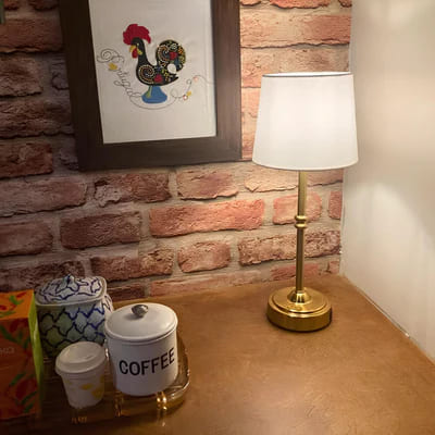 AMBIENTIFY Classic cordless table lamp with fabric shade and iron stem, casting warm ambient light on a bedside table. Three brightness settings and up to 40 hours battery life. Suitable for bedroom, living room and home office.